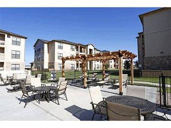 A patio with chairs and a table is in front of a building.